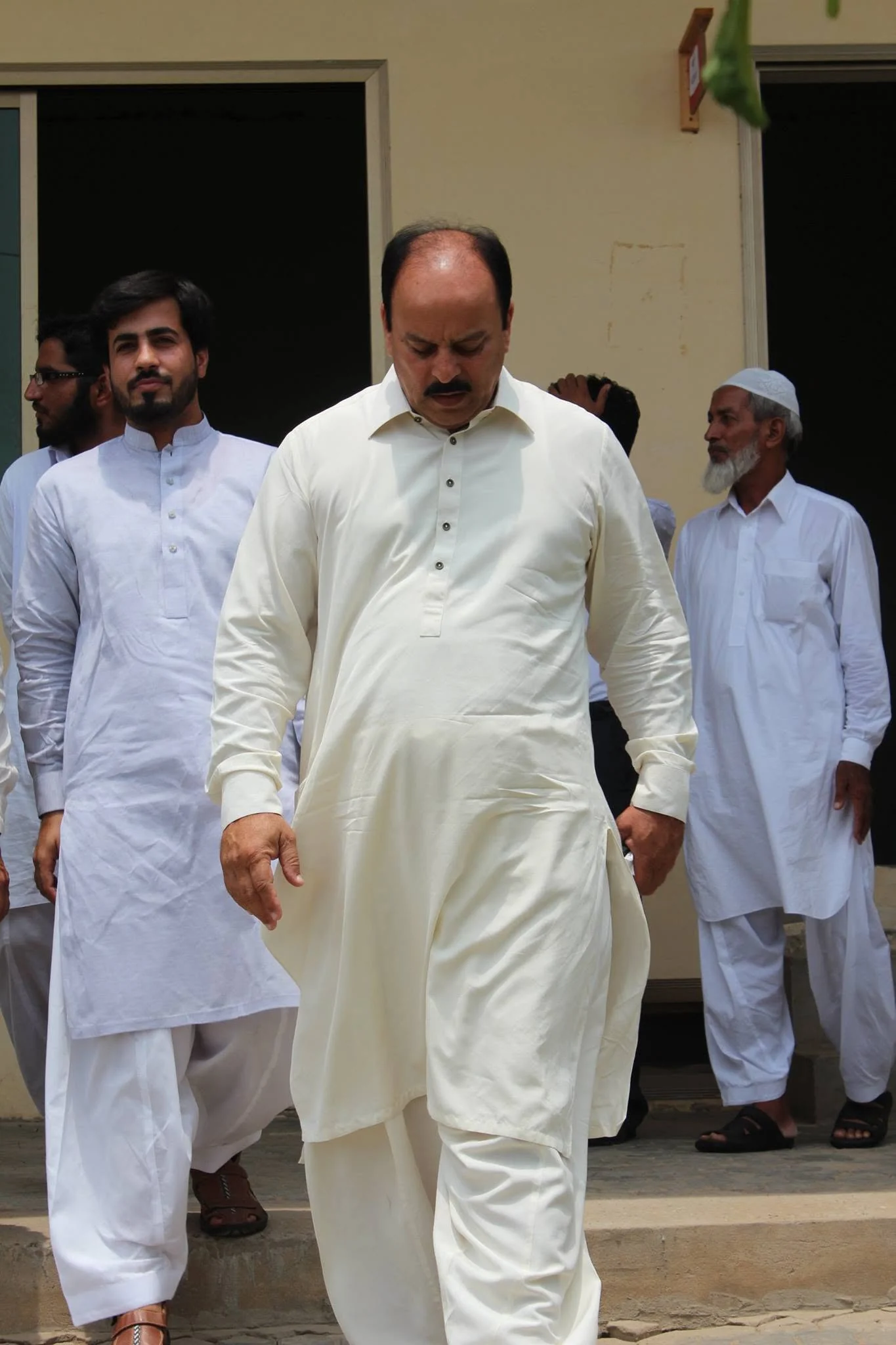 Ch. Muhammad Aslam Sikho walking through the Danish International Grammar School campus with Faruukh Nadeem during the 2014 visit.