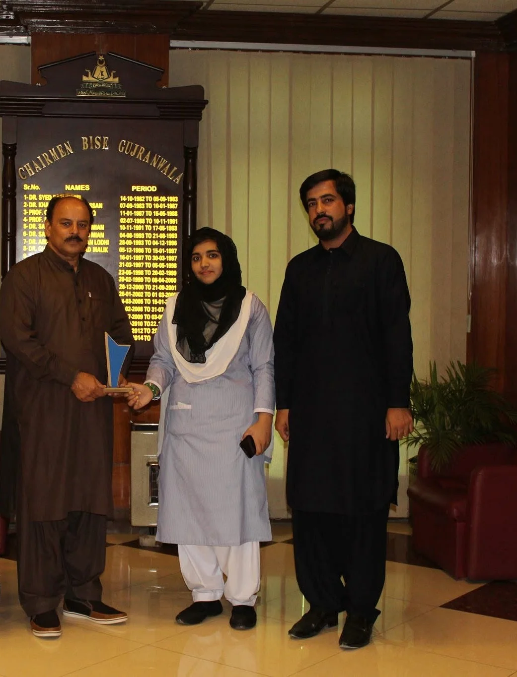 A second full office photograph showing the BISE Gujranwala Chairman, the student and Faruukh Nadeem during the formal recognition.